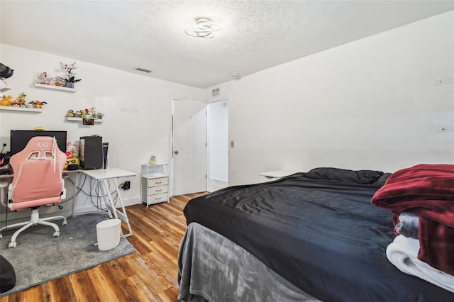 bedroom with a textured ceiling and light hardwood / wood-style flooring