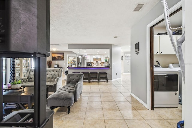 tiled living room featuring a textured ceiling and washer and dryer