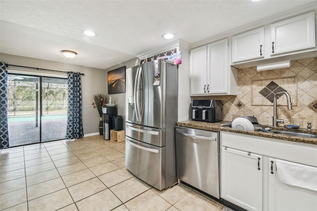 kitchen featuring sink, white cabinetry, stainless steel appliances, light tile patterned floors, and dark stone counters