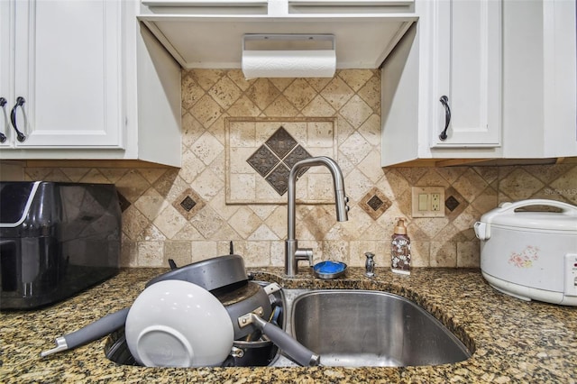 kitchen with decorative backsplash, white cabinetry, and dark stone countertops