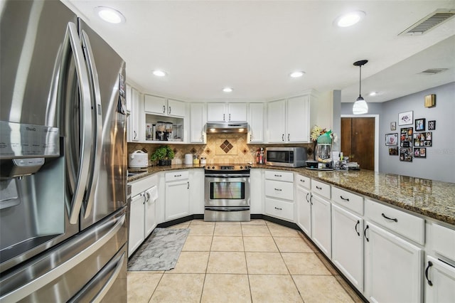 kitchen with light tile patterned flooring, appliances with stainless steel finishes, dark stone countertops, and white cabinets