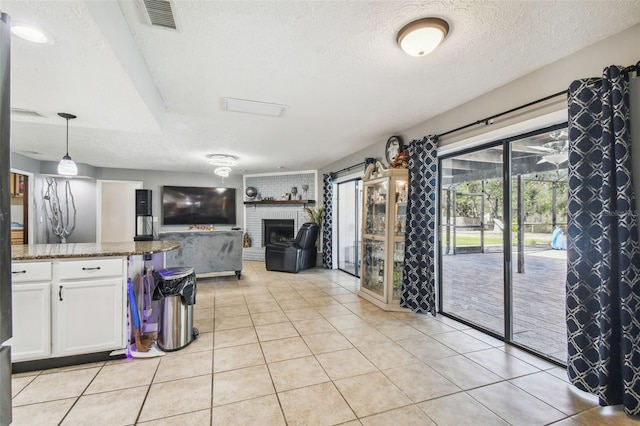 kitchen featuring light tile patterned flooring, hanging light fixtures, dark stone counters, a textured ceiling, and white cabinets