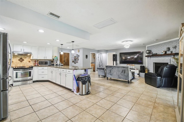 kitchen with light tile patterned floors, stainless steel appliances, dark stone counters, pendant lighting, and white cabinets