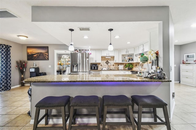 kitchen featuring stainless steel refrigerator with ice dispenser, backsplash, light tile patterned flooring, dark stone counters, and white cabinets