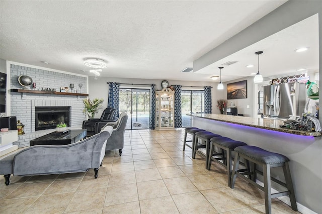 living room featuring a fireplace, a textured ceiling, and light tile patterned flooring