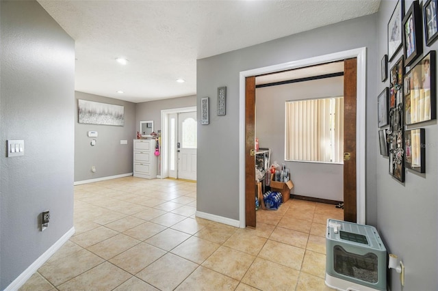 hallway featuring a textured ceiling, light tile patterned floors, and heating unit