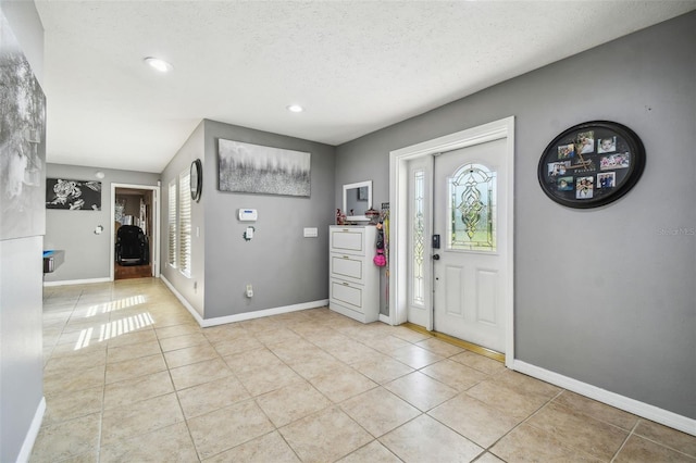 tiled entryway with a textured ceiling and a healthy amount of sunlight