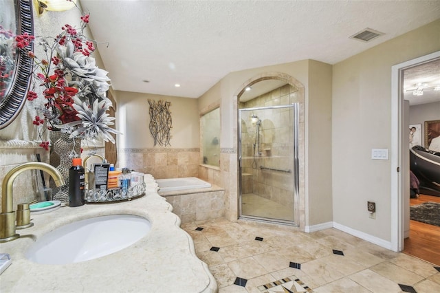 bathroom with sink, a textured ceiling, tile patterned floors, and plus walk in shower