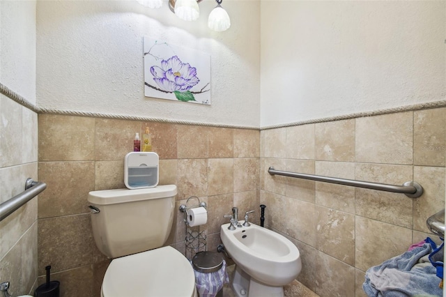 bathroom with toilet, tile walls, and a bidet