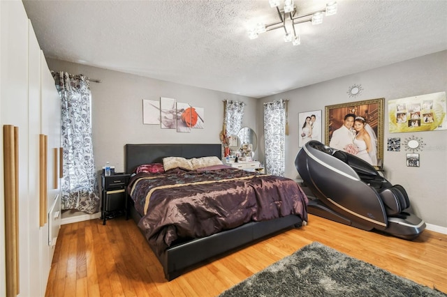 bedroom with a textured ceiling, hardwood / wood-style floors, and multiple windows