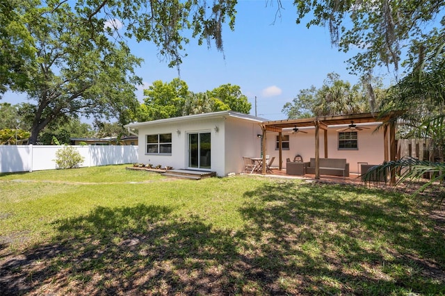 rear view of property featuring a yard, ceiling fan, and an outdoor living space