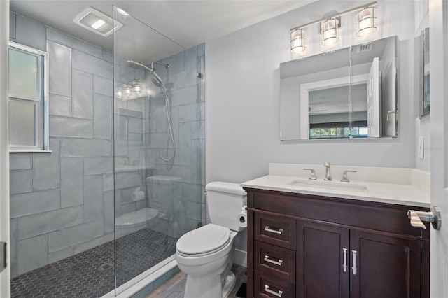 bathroom with a tile shower, vanity, and toilet