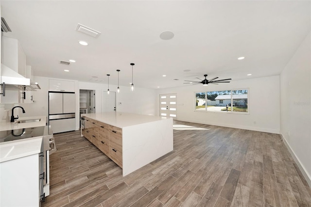 kitchen with sink, white refrigerator, decorative light fixtures, white cabinets, and range