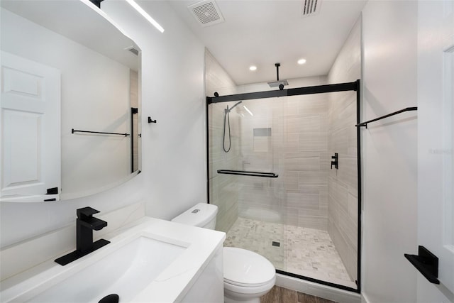 bathroom with an enclosed shower, vanity, toilet, and hardwood / wood-style flooring