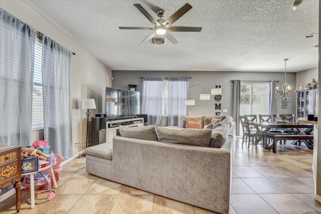 living room featuring a textured ceiling, ceiling fan with notable chandelier, and light tile patterned flooring