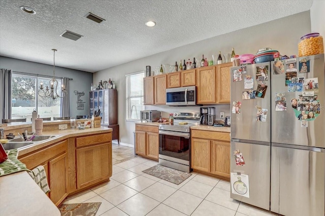 kitchen with sink, decorative light fixtures, a textured ceiling, a notable chandelier, and stainless steel appliances