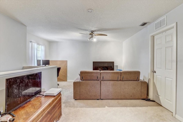 carpeted living room featuring a textured ceiling and ceiling fan