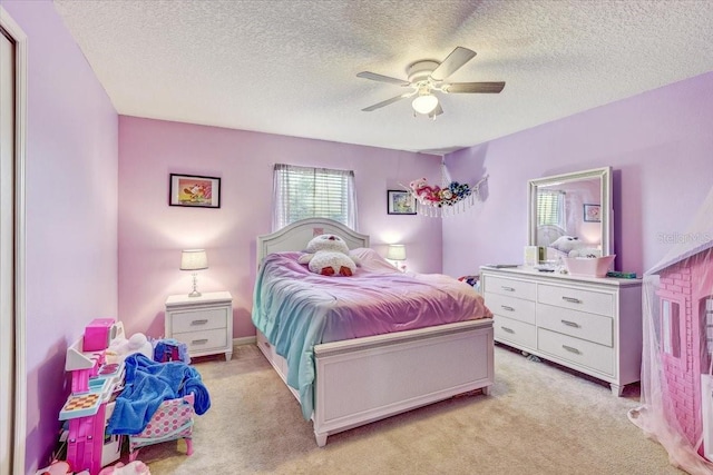 bedroom featuring a textured ceiling, light colored carpet, and ceiling fan