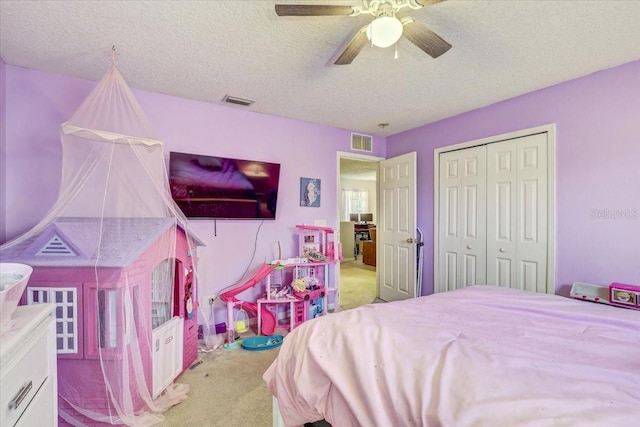 carpeted bedroom with ceiling fan, a closet, and a textured ceiling