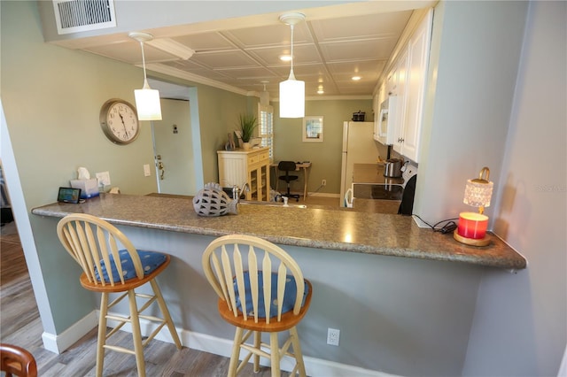 kitchen with hardwood / wood-style floors, stove, hanging light fixtures, and a kitchen breakfast bar