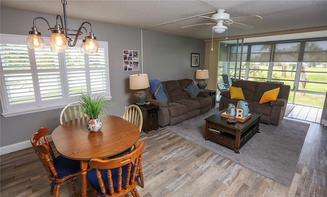 living room featuring ceiling fan with notable chandelier, wood-type flooring, and a textured ceiling