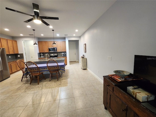 dining area featuring ceiling fan, sink, and light tile patterned floors