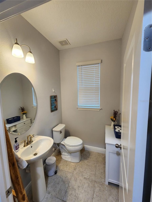 bathroom featuring a textured ceiling, toilet, and tile patterned flooring