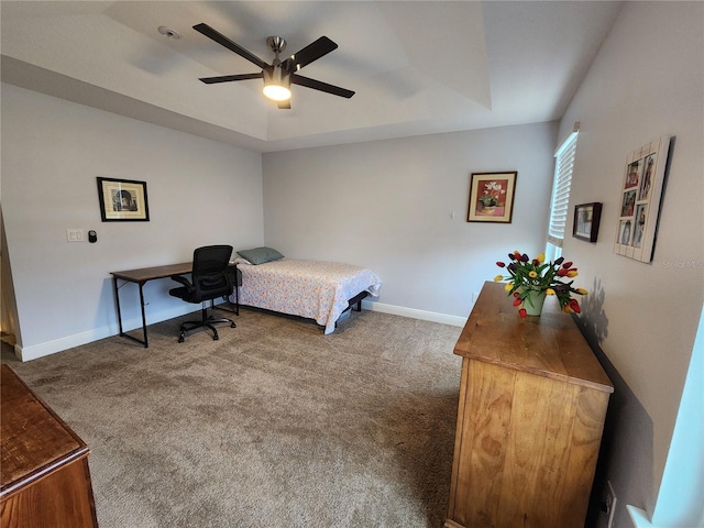 carpeted bedroom with a raised ceiling and ceiling fan