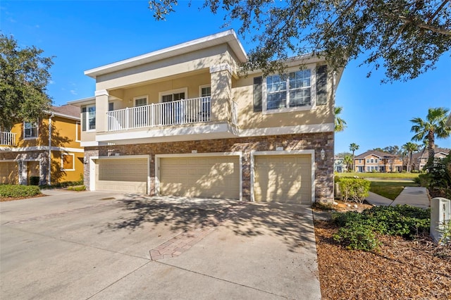 7001 Interbay Blvd Unit 313, Tampa, FL 33616 - view of front of home featuring an attached garage, stone siding, stucco siding, concrete driveway, and a balcony