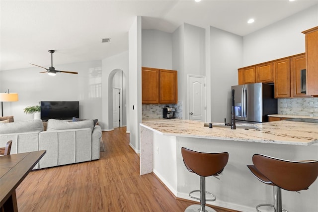 7001 Interbay Blvd Unit 313, Tampa, FL 33616 - kitchen with stainless steel fridge, brown cabinetry, a kitchen breakfast bar, and backsplash