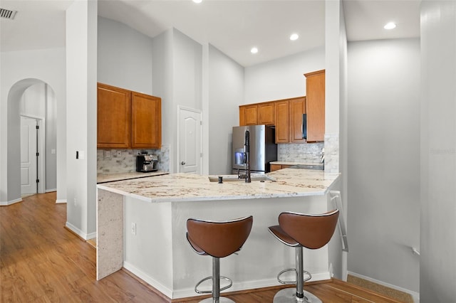 7001 Interbay Blvd Unit 313, Tampa, FL 33616 - kitchen with stainless steel fridge, a peninsula, decorative backsplash, brown cabinets, and recessed lighting