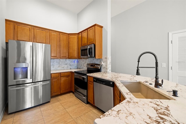 7001 Interbay Blvd Unit 313, Tampa, FL 33616 - kitchen featuring stainless steel appliances, light stone counters, backsplash, brown cabinetry, and light tile patterned flooring