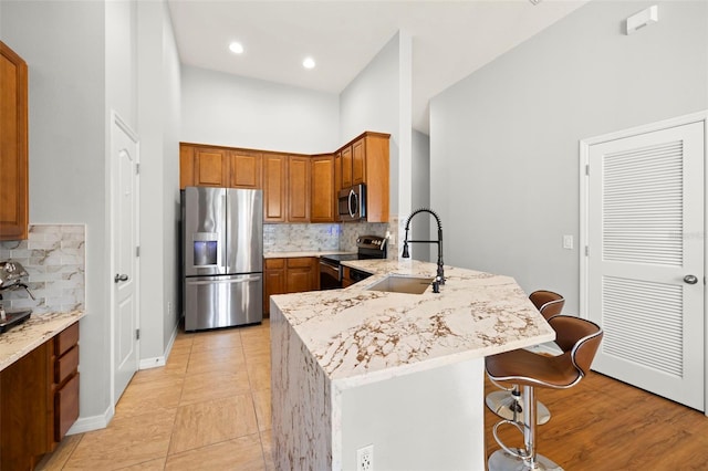 7001 Interbay Blvd Unit 313, Tampa, FL 33616 - kitchen featuring stainless steel appliances, a peninsula, a kitchen breakfast bar, tasteful backsplash, and brown cabinetry