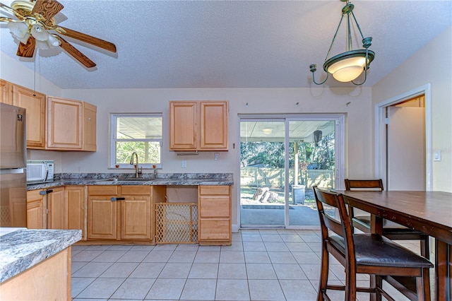 kitchen with light brown cabinetry, sink, and a textured ceiling