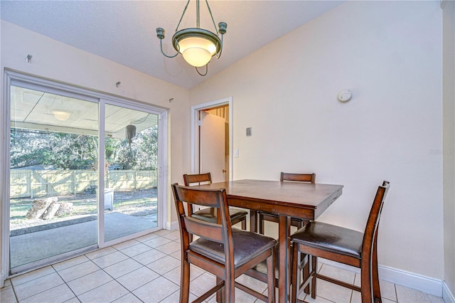 dining area with a textured ceiling, lofted ceiling, and light tile patterned flooring