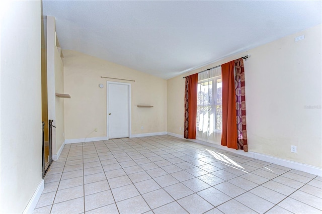 tiled empty room featuring lofted ceiling