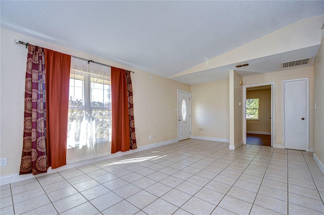 tiled spare room featuring a textured ceiling and lofted ceiling