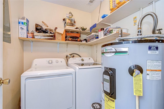 washroom with washing machine and dryer, electric water heater, and a textured ceiling