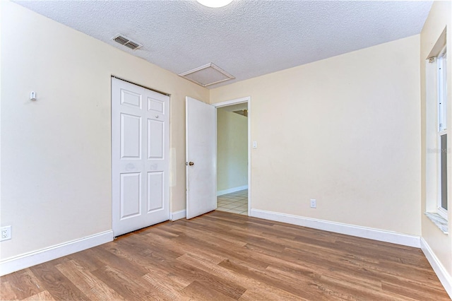 unfurnished bedroom with wood-type flooring, a textured ceiling, and a closet