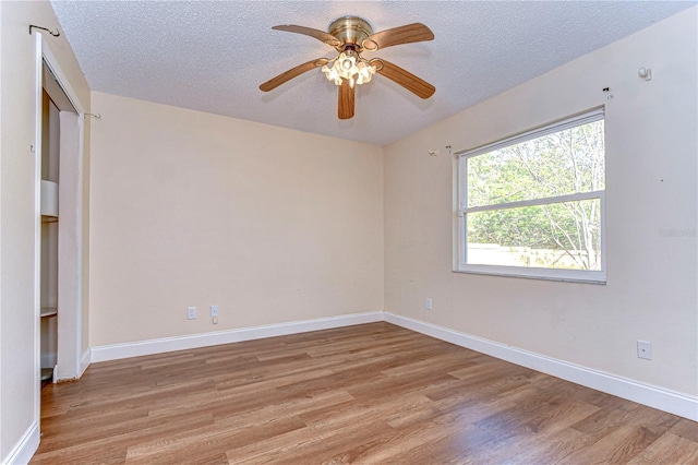 spare room featuring ceiling fan, light wood-type flooring, and a textured ceiling