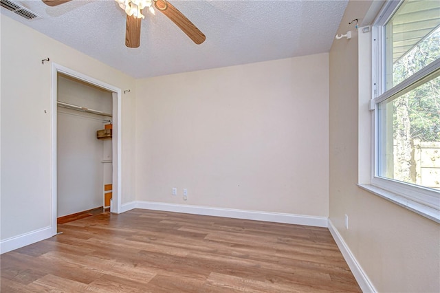 unfurnished bedroom featuring a closet, ceiling fan, light hardwood / wood-style flooring, and a textured ceiling