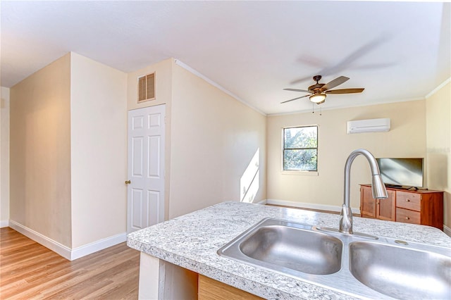 kitchen featuring sink, ceiling fan, light wood-type flooring, ornamental molding, and a wall unit AC