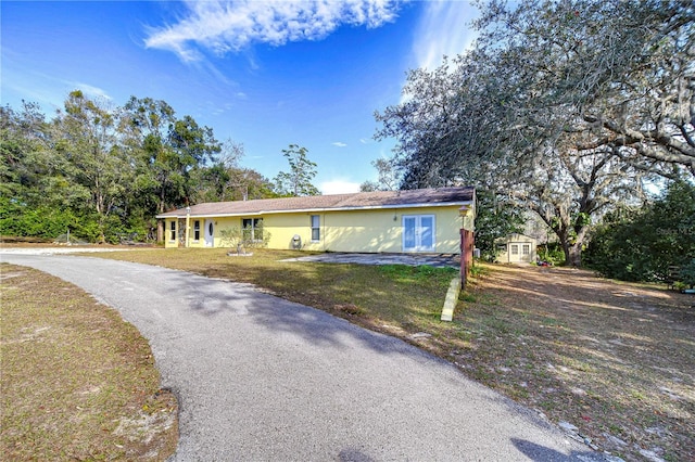 single story home featuring a storage shed and a front yard