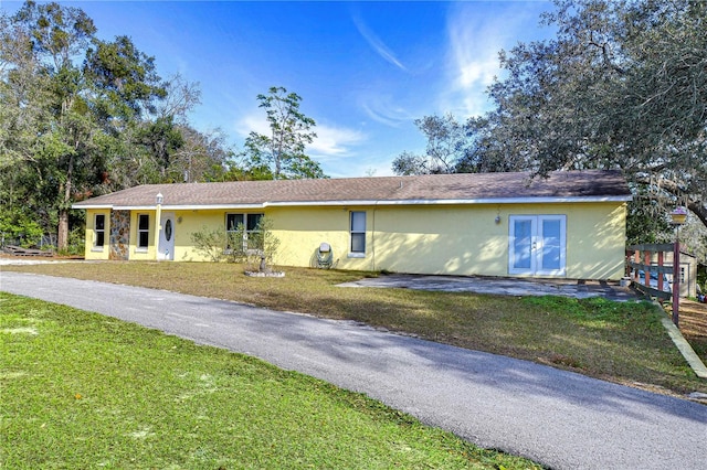 view of front of home with stucco siding, a front lawn, and french doors