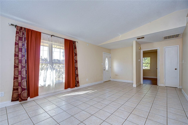 empty room featuring vaulted ceiling, a textured ceiling, and visible vents