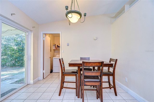 dining area featuring washer / dryer, light tile patterned flooring, vaulted ceiling, and baseboards