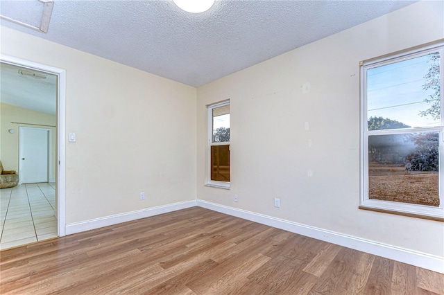 spare room featuring baseboards, wood finished floors, and a textured ceiling