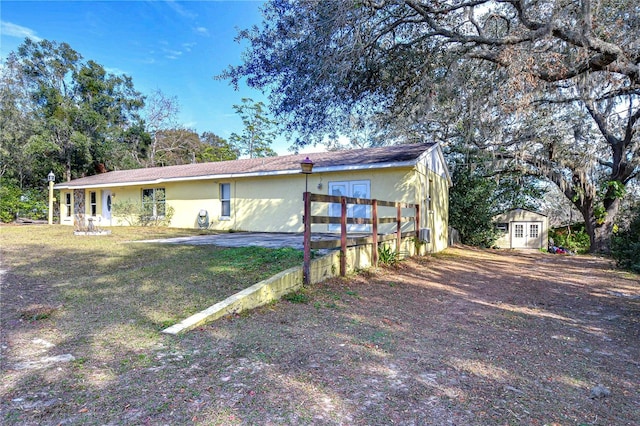 rear view of property featuring stucco siding, an outdoor structure, and a storage shed
