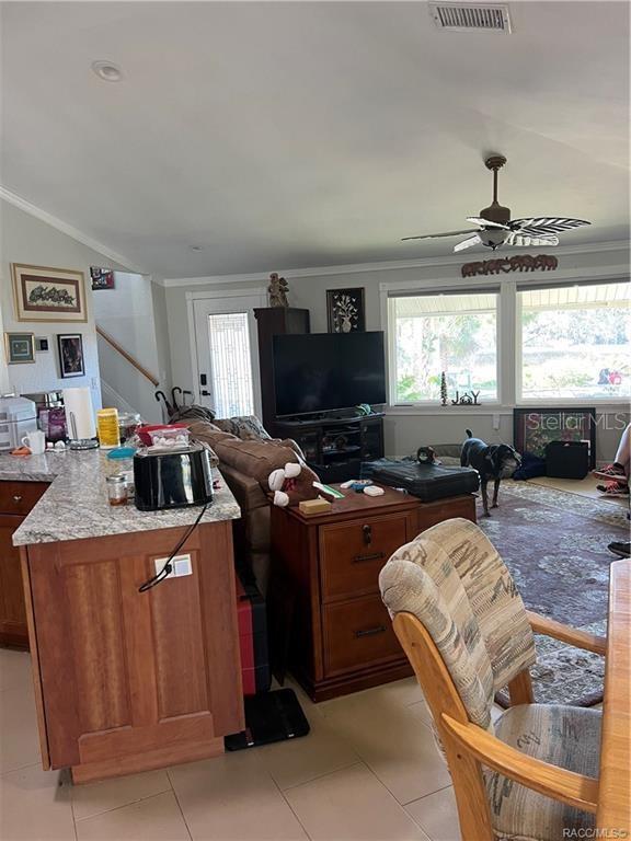 kitchen with ceiling fan, crown molding, light tile patterned flooring, and vaulted ceiling