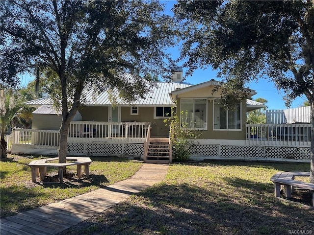 rear view of house featuring a lawn, a sunroom, and a deck